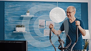 Aged man riding stationary bicycle for endurance and sport