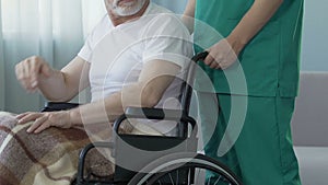 Aged man sitting in wheelchair at nursing home, feeling lonely and forgotten