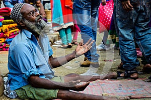 Aged man with specs begging on the street due to having paraplegia, both legs paralysis