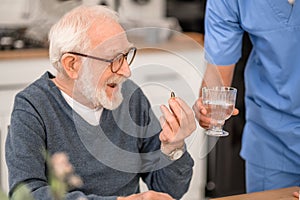 Aged man taking a medicine supervised by a medical worker