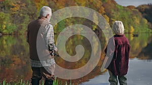 Aged man and teen boy talking and smiling while fishing