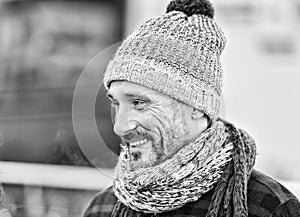 Aged man in winter hat and scarf. Portrait of smiling guy on street. Guy in knitted scarf and hat