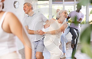 Aged man and woman dancing jive during group training