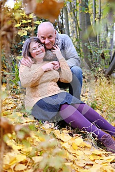 Aged man and woman hugged in the autumn park against the background of trees, the concept of a healthy lifestyle, good mood,