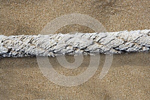 Aged marine rope over beach sand background
