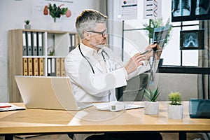 Aged medical specialist examining results of x ray scan