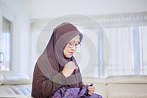 Aged Muslim woman using a needle to sewing a cloth