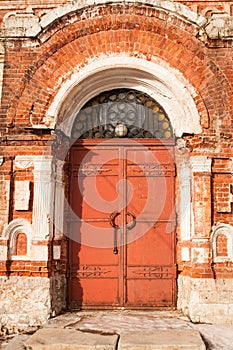 Aged Old Red Metal Door With Lock On Old Brick Facade.