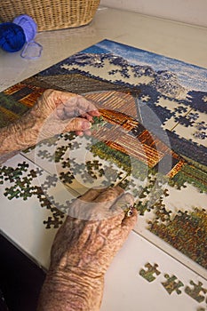 Aged person hands with jigsaw puzzle