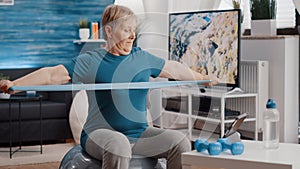 Aged person pulling resistance band on fitness toning ball