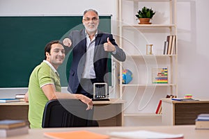 Aged physics teacher and male student in the classroom