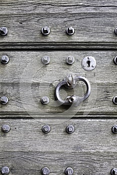 Aged planks with old rivets, bolts, door handle. The gothic door in the medieval teutonic knights castle Malbork, Poland.