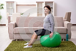 The aged pregnant woman doing exercises at home