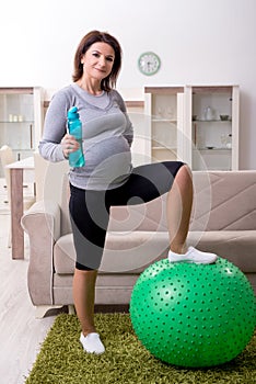 The aged pregnant woman doing exercises at home