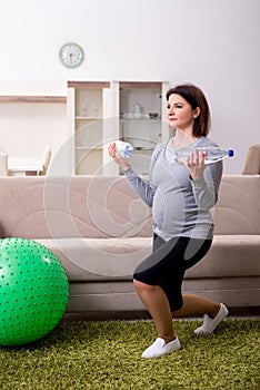 Aged pregnant woman doing exercises at home