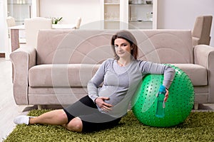 Aged pregnant woman doing exercises at home