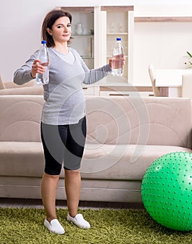 Aged pregnant woman doing exercises at home