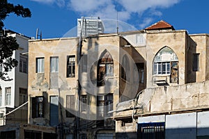 Aged residential building with weathered facade under clear blue sky in central Tel Aviv