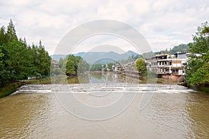 Aged riverside town in cloudy autumn morning