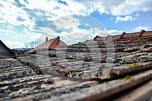 Aged roofing tiles on old house in village on blue cloudy sky