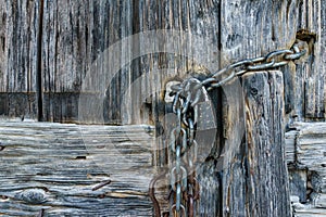 Aged rusty chain with lock pad on old ancient wooden door