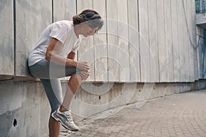 Aged slim woman hurting knee joint while running