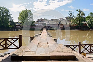 Aged stone beam bridge across river in sunny autumn