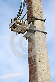 Aged three-phase electric switch is installed on a rustic concrete column