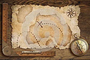 Aged treasure map, ruler and old bronze compass on table