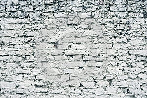 Aged white painted brick wall texture. Old textured grunge wall surface background pattern of masonry. Cracks and black stains.