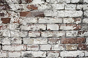 Aged white painted brick wall texture. Old textured grunge wall surface background pattern of masonry. Cracks and black stains.