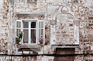 Aged windows and flower boxes of historical building from old town of Pula, Croatia / Detail of ancient venetian architecture.