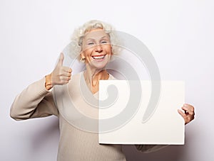 Aged woman with blank advertising board or copy space.