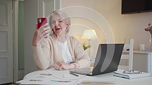 An aged woman communicates on a video call, and then waves her hand and says goodbye