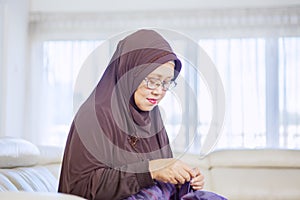 Aged woman enjoy leisure time while sewing at home