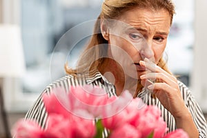 Aged woman with facial wrinkles feeling bad having allergy to tulips