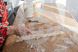 Aged woman hands with a rolling pin preparing the casadielles dough at home. Tradicional gastronomy