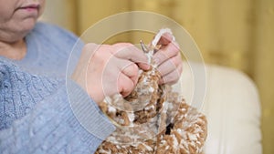 aged woman knitting a scarf, hands closeup