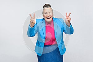 Aged woman laugh and showing peace or victory sign at camera