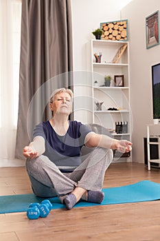 Aged woman practicing yoga at home