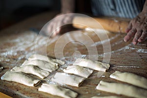 Aged woman`s hands with a rolling pin preparing at home casadielles filled with nuts. Tradicional gastronomy photo