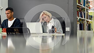Aged woman, senior intern looking uncertain, confused at the screen while using laptop, sitting at desk, working in