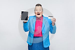 Aged woman showing tablet screen and credit card