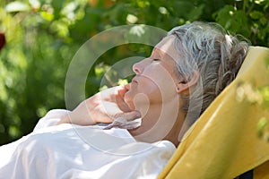 Aged woman sleeping on lounger