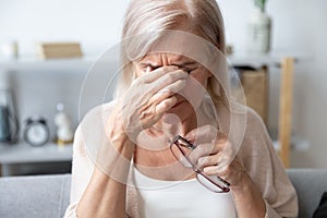 Aged woman taking off glasses rubbing eyelid suffers from eyestrain