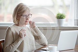 Aged woman using laptop confused seeing error message