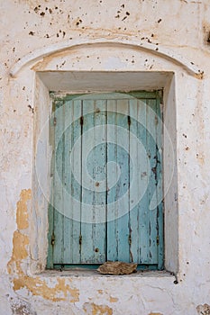 Aged wooden closed shutters, peeled building wall facade, stone keep the window shut. Vertical