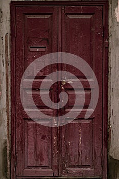 Aged wooden door painted maroon. Vintage house facade with a door. Wood vinous texture of a door. Old burgundy grunge texture