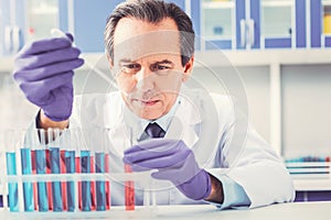 Ageing chemist placing test tubes in order