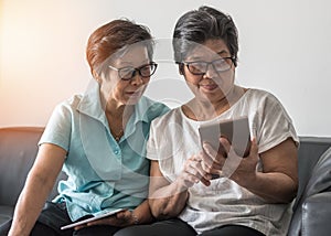 Ageing society concept, Asian elderly senior adult women sisters using mobile digital tablet smart phone application